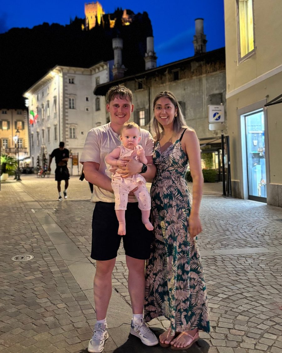 Chris en Manita met Noë op de arm, op een avond in een Italiaans stadje, met een verlicht kasteel op de berg erachter
